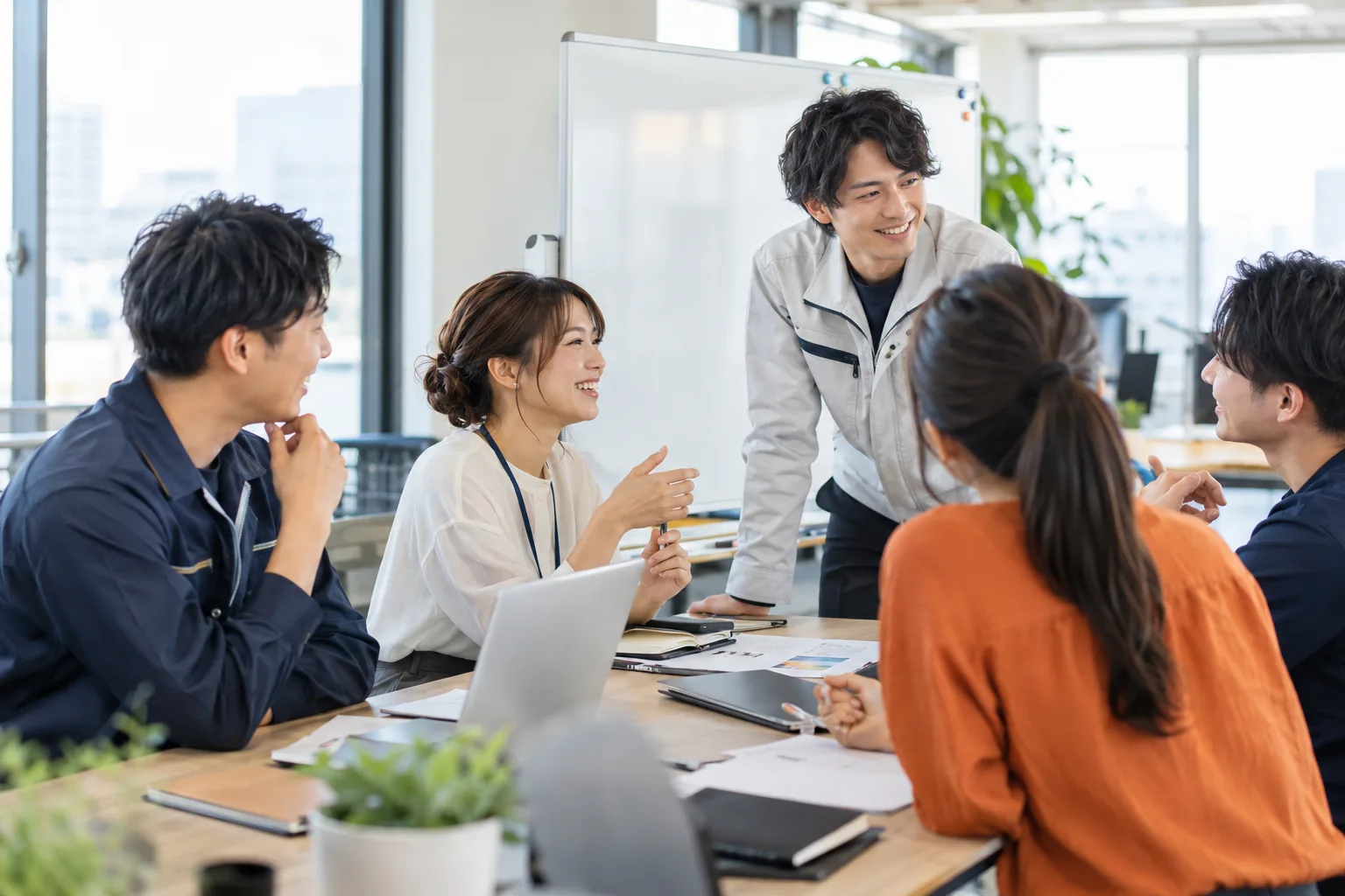明るいオフィスで、ホワイトボードの前で話し合う社員たち